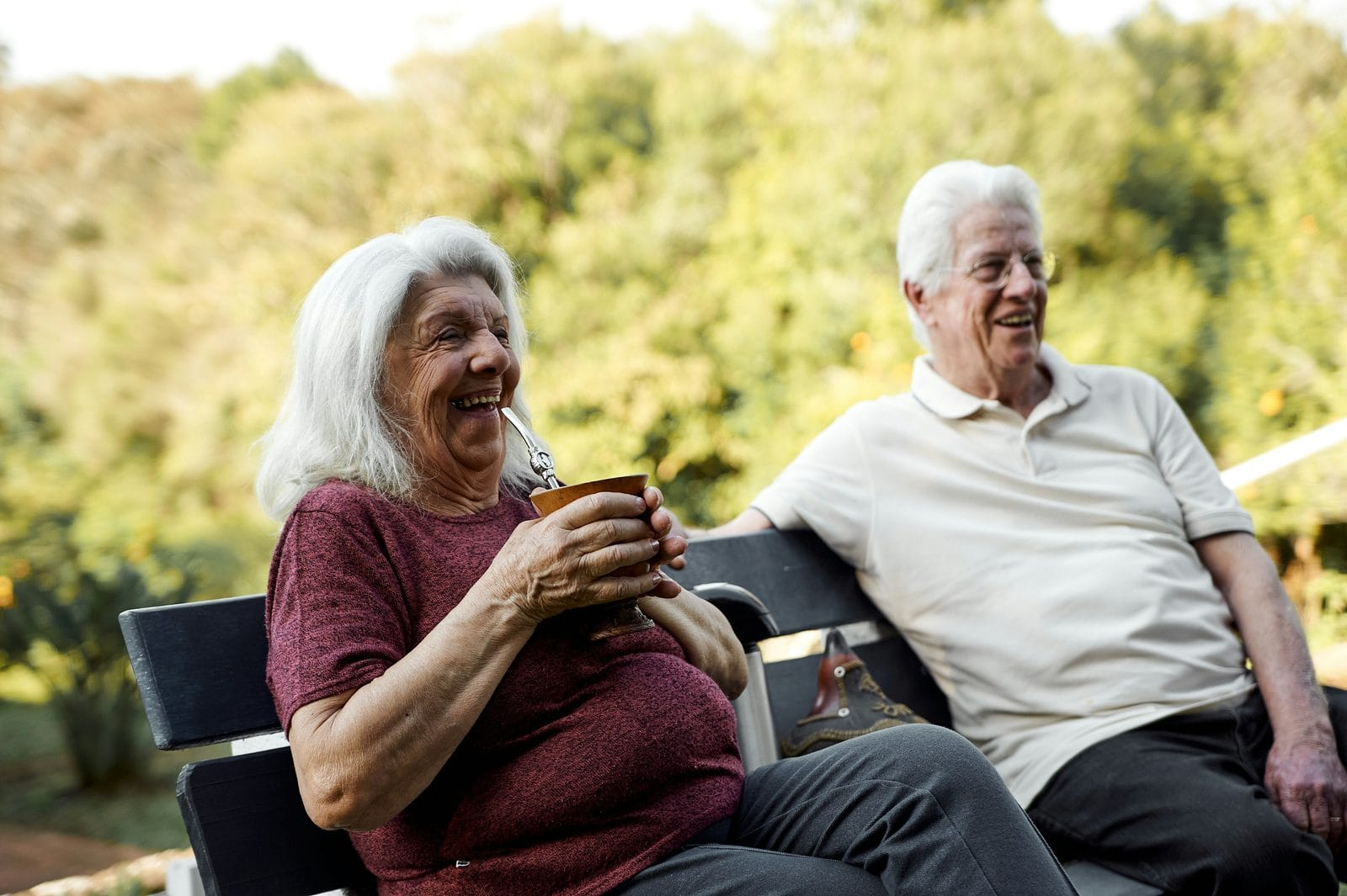 A couple sitting side by side on a bench outdoors, talking A couple sitting side by side on a bench outdoors, talking