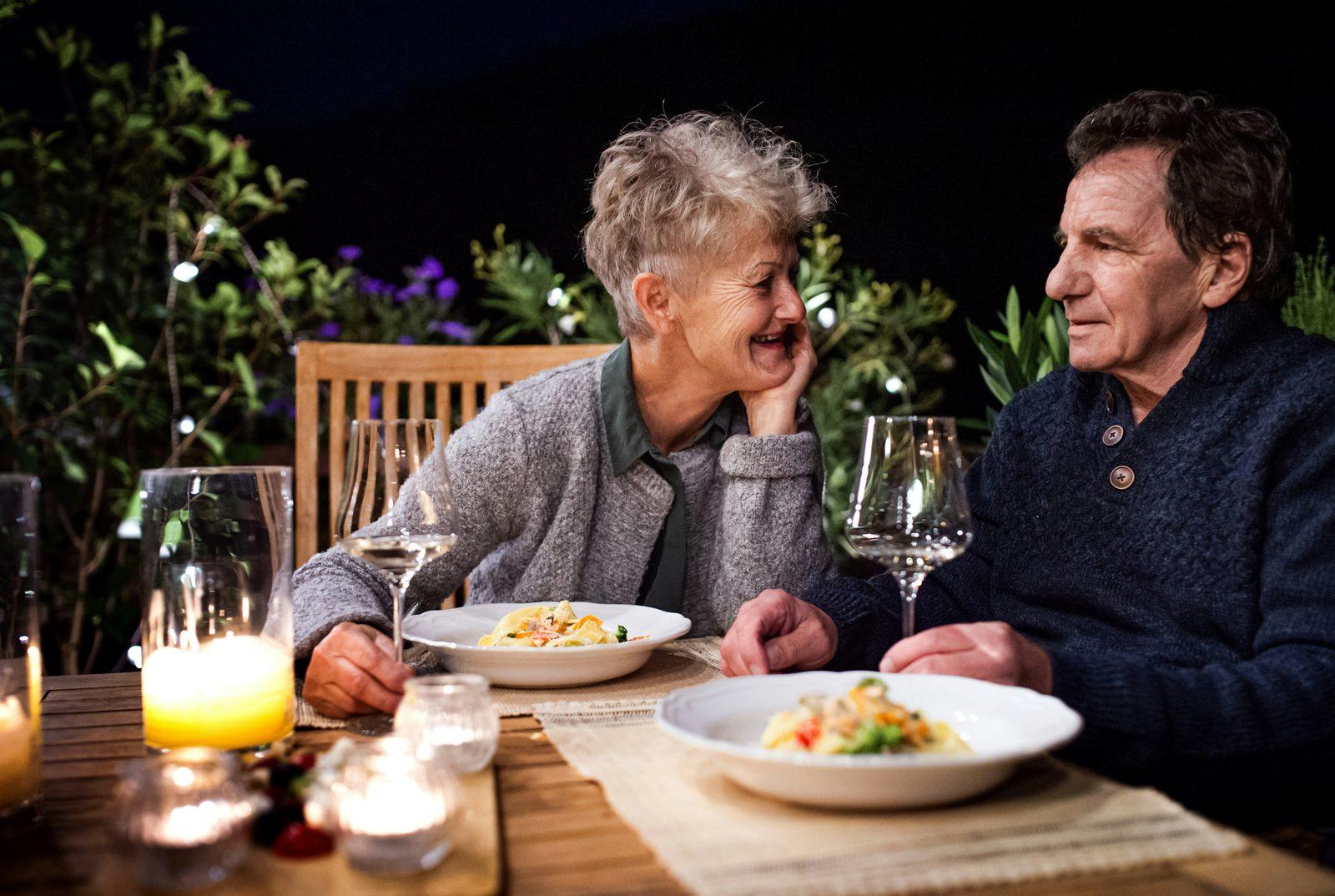 A couple in conversation over a candlelit dinner outdoors