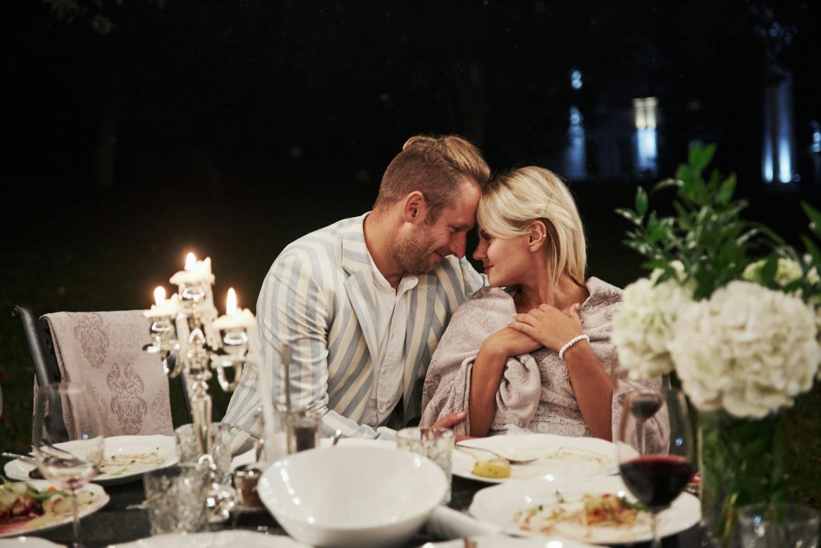 A couple at a candlelit table with white flowers