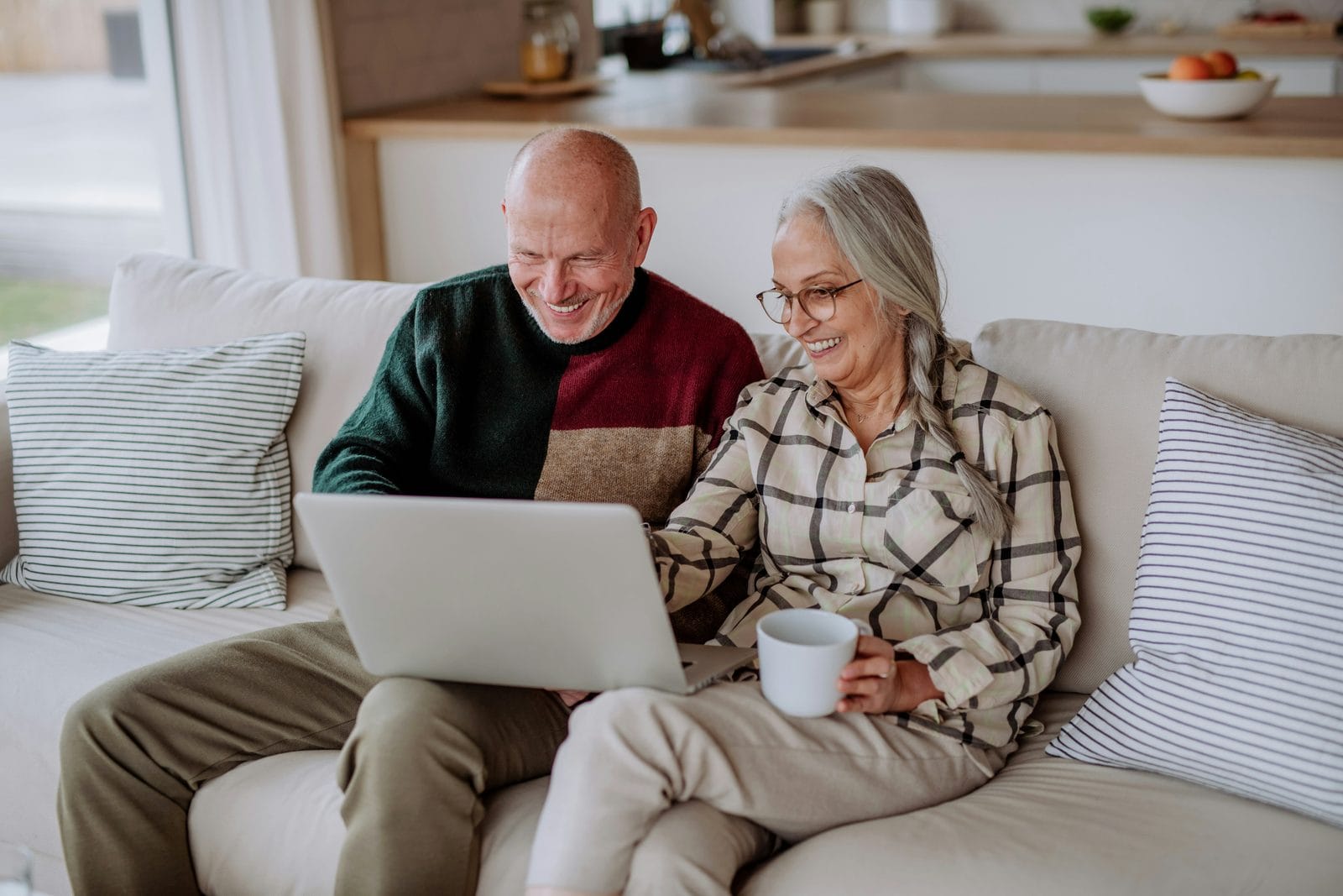 An older couple looking at a laptop together on a sofa