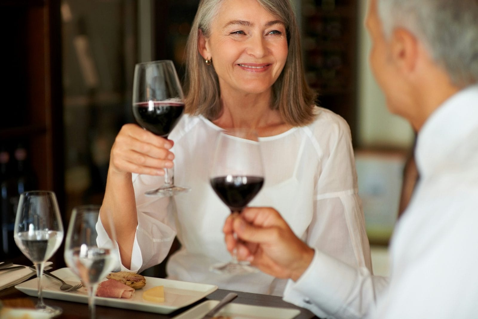 A man and a woman in conversation at a table with wine glasses A man and a woman in conversation at a table with wine glasses