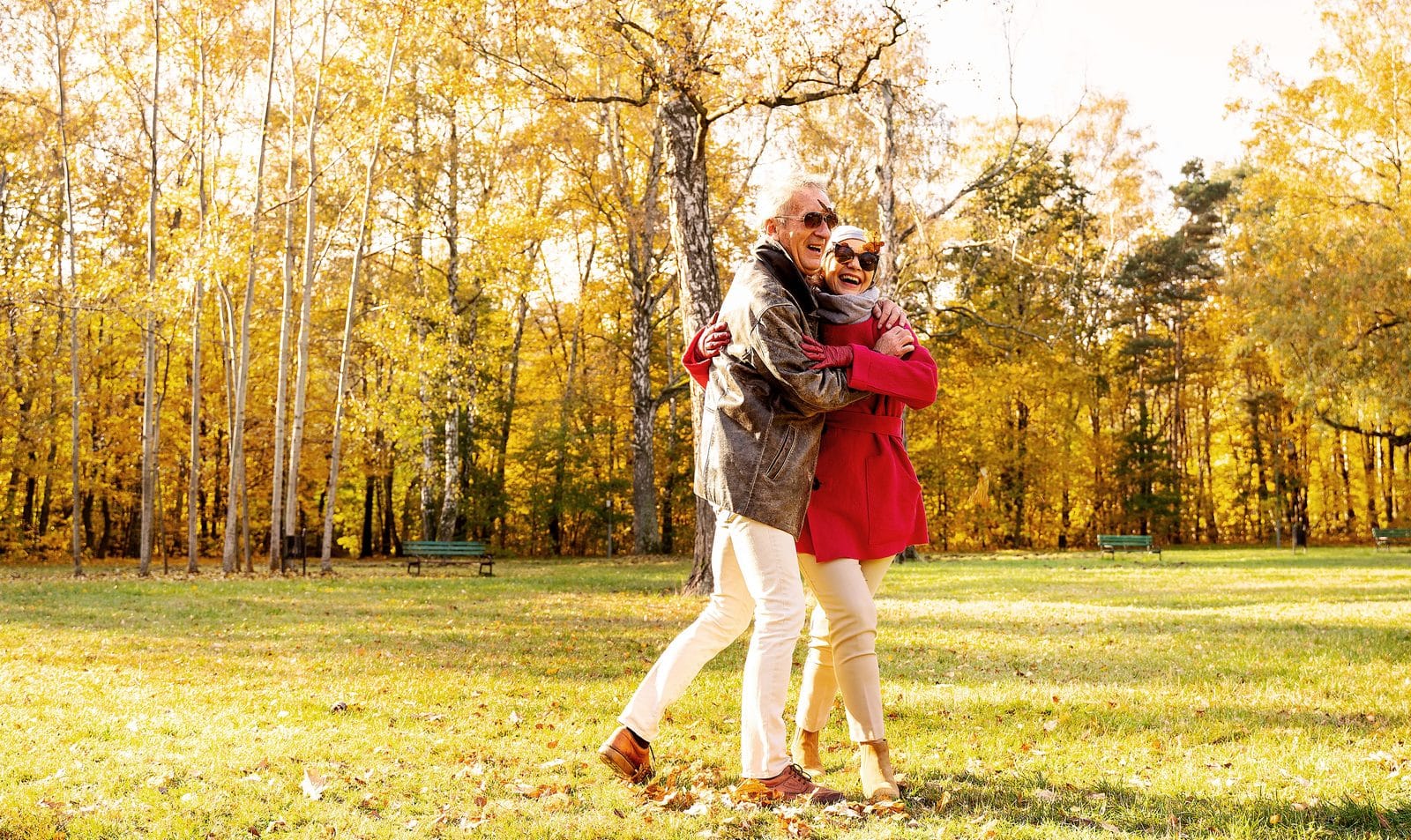 An older man and woman walking together in a park An older man and woman walking together in a park