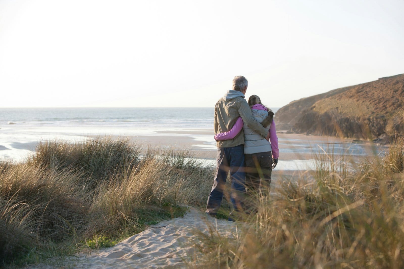 An older couple walking together along a coastal path