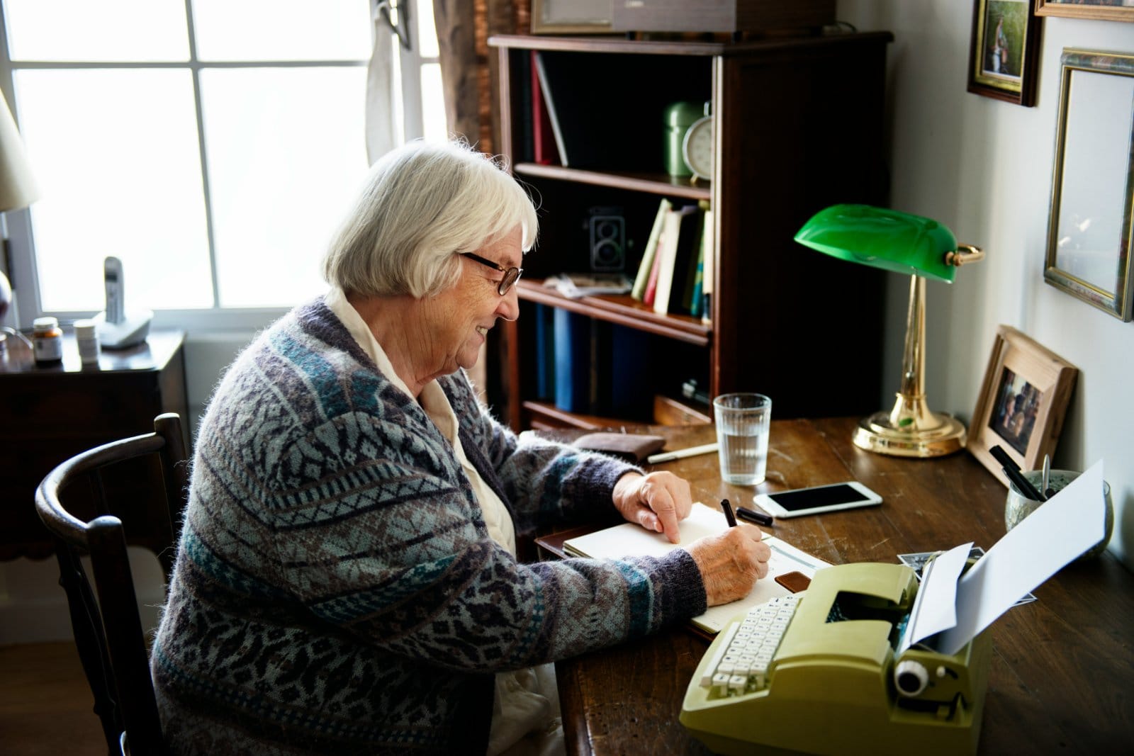 A woman writing at a desk with a reading lamp