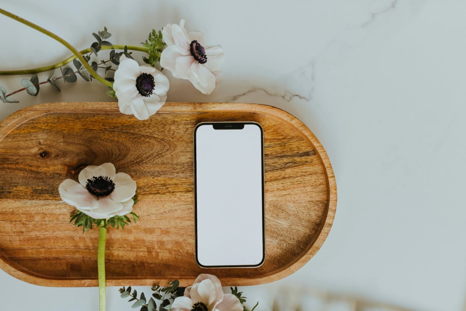 Flowers and a phone laid out on a wooden board