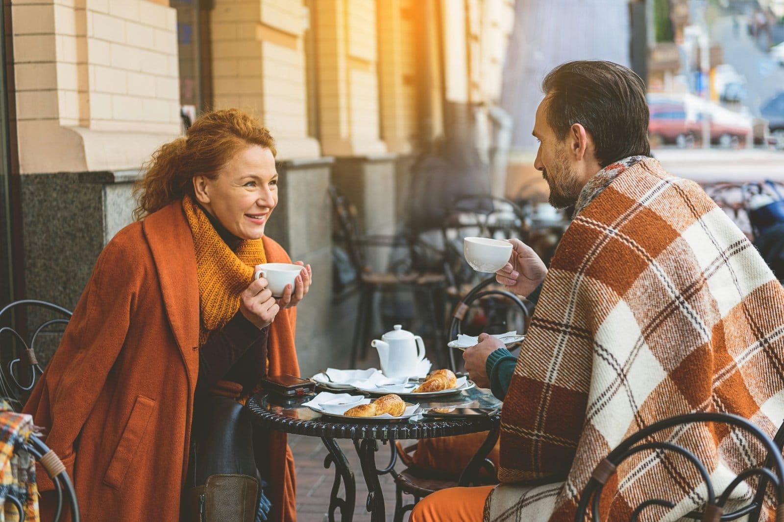 Two people in their fifties talking over coffee at an outdoor table