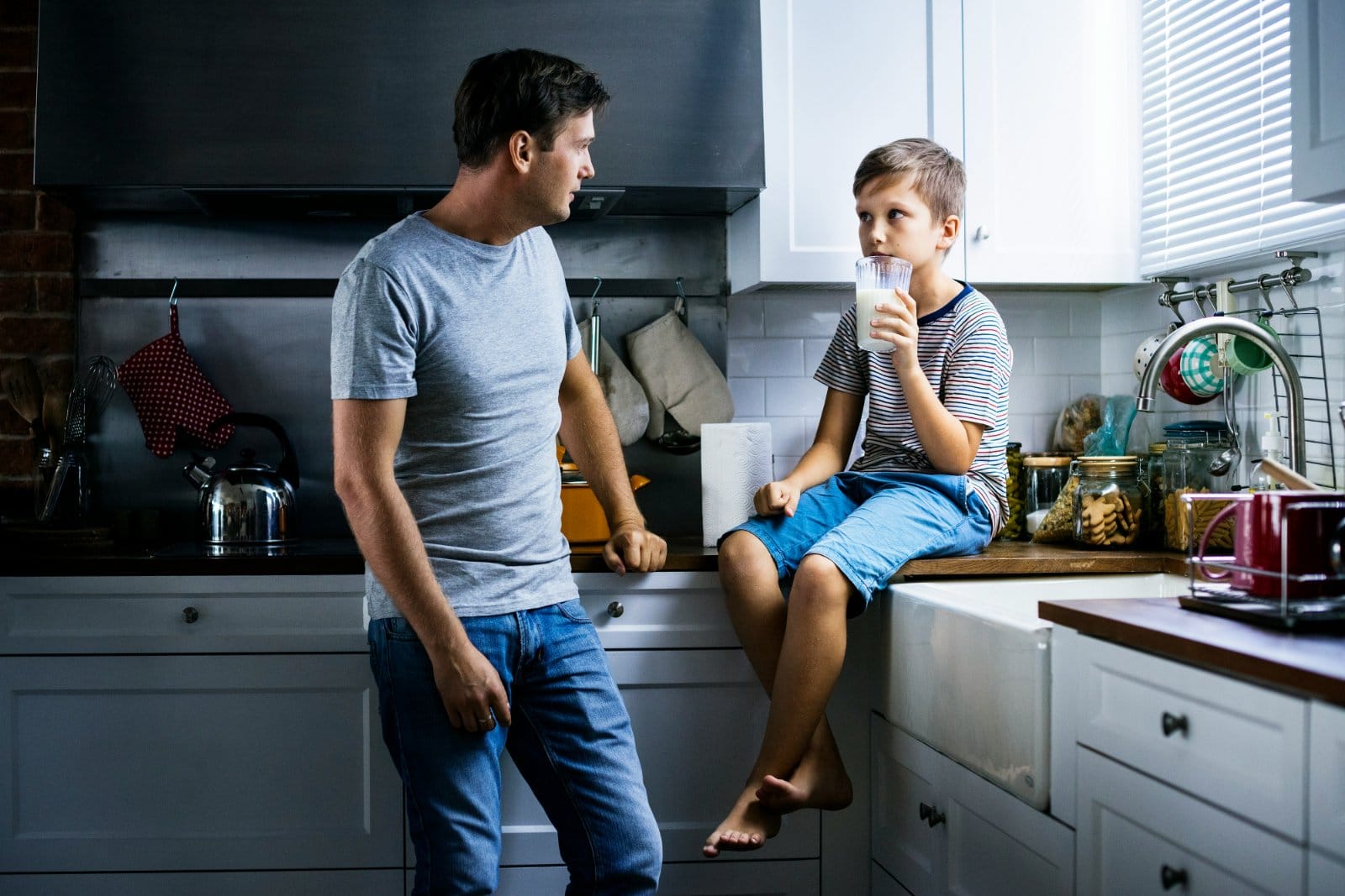 A father and his teenage son talking in a kitchen