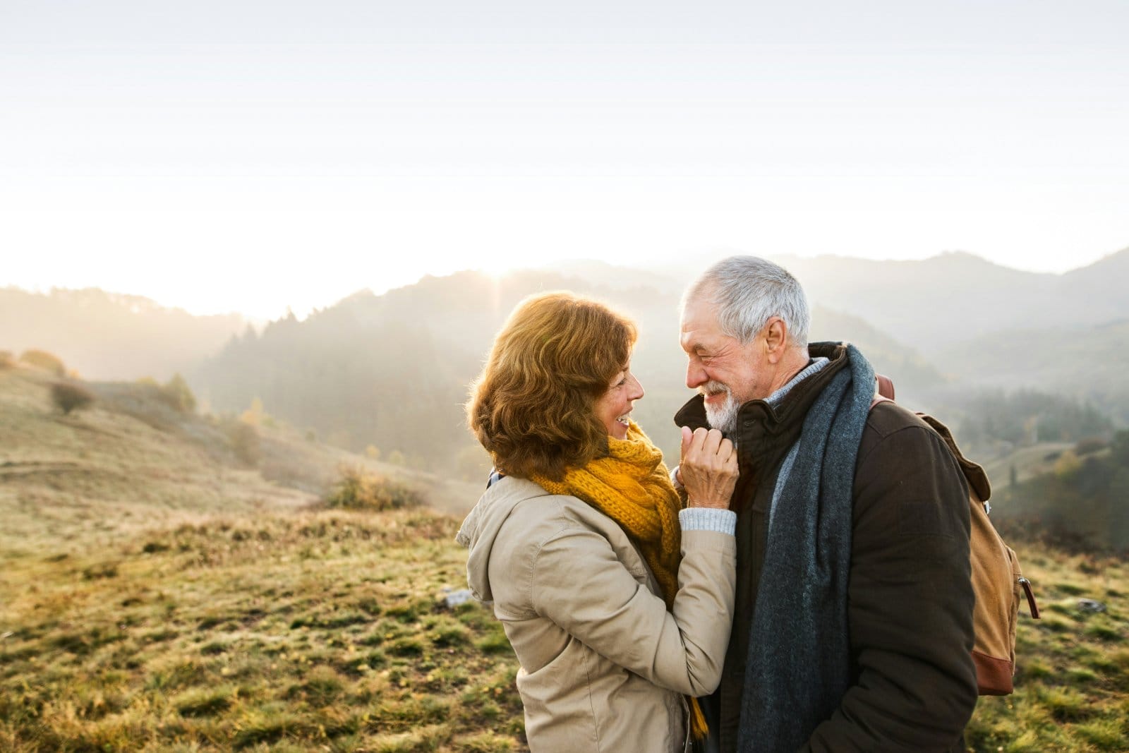 An older couple walking together outdoors in late afternoon light