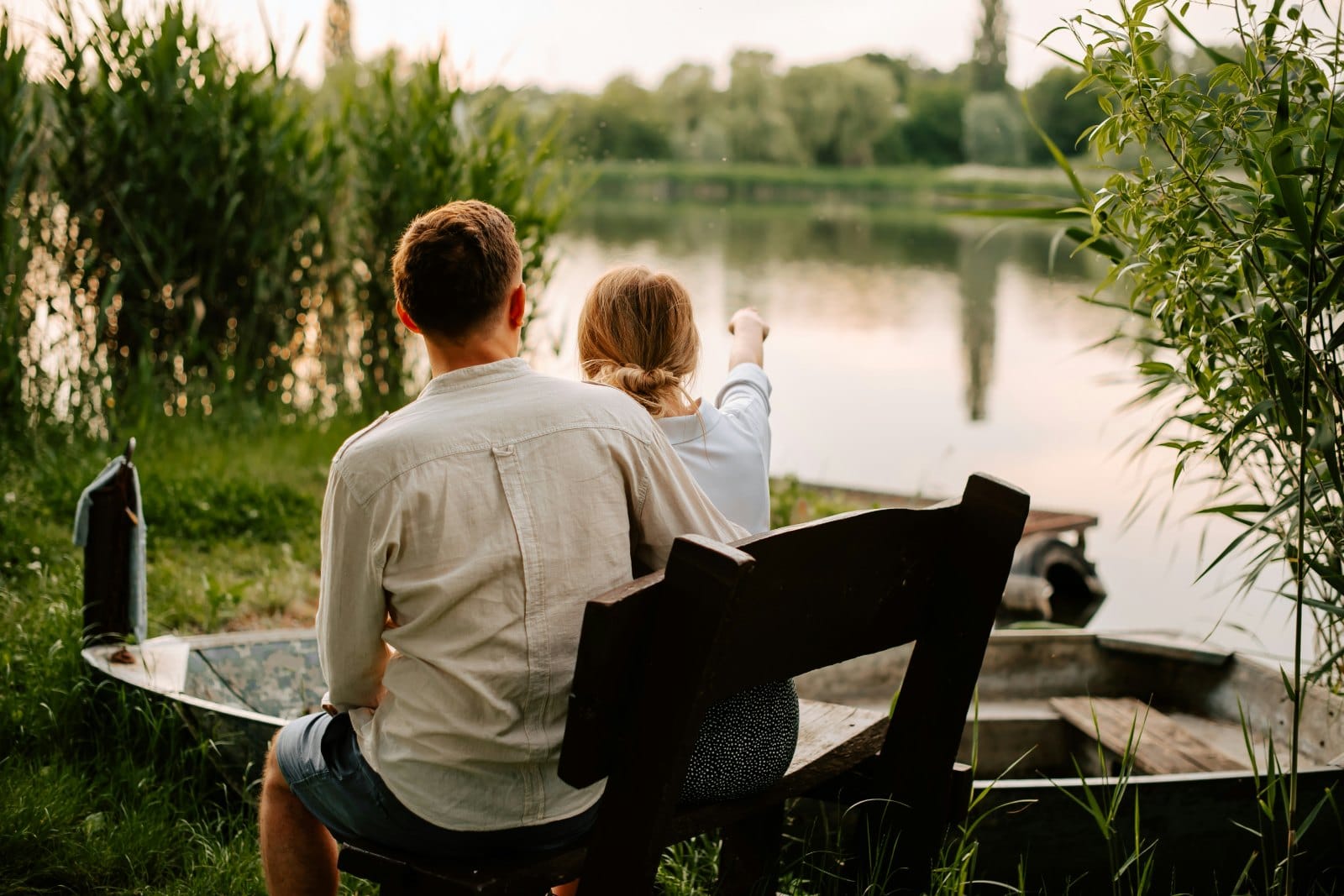 A man and a woman sitting together on a bench looking out over a lake
