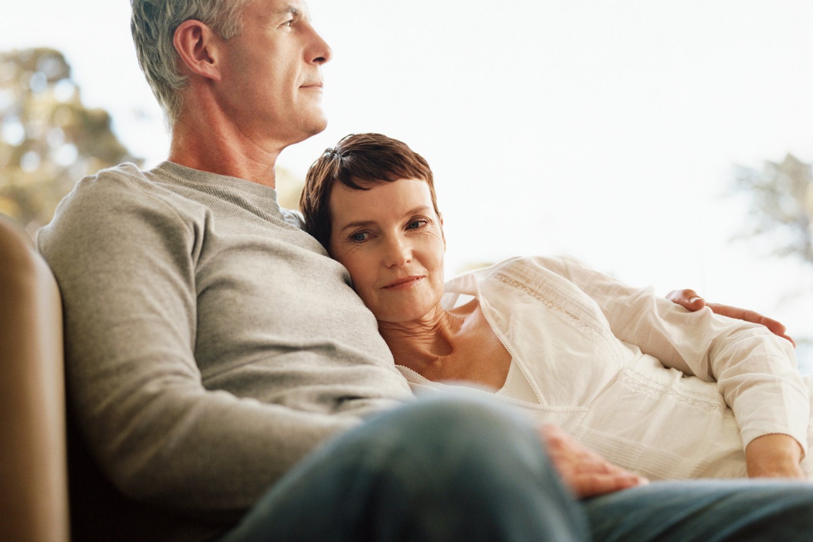 A couple in their fifties sitting close together on a sofa, quiet after a conversation