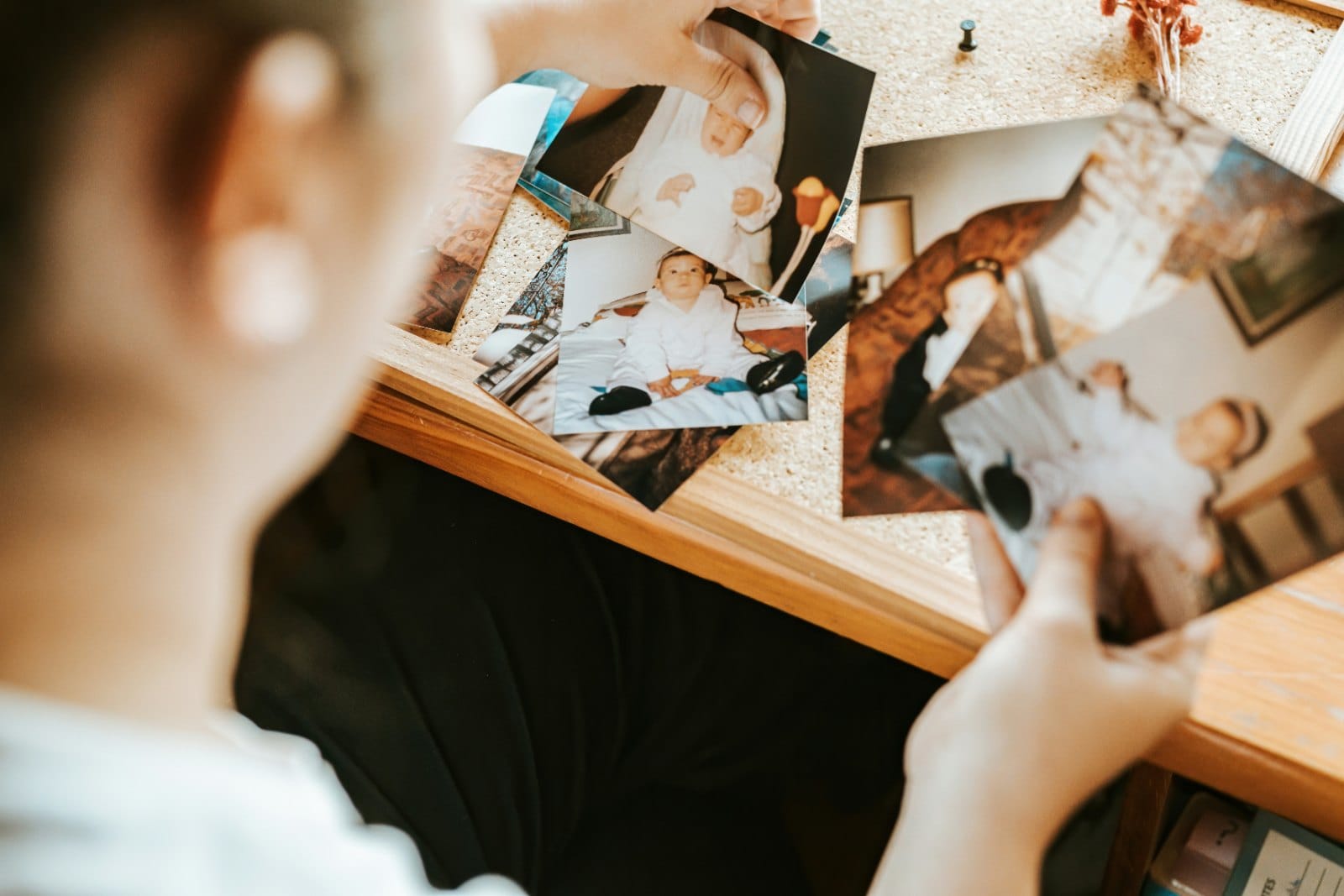 A person looking through a set of old family photographs spread on a table