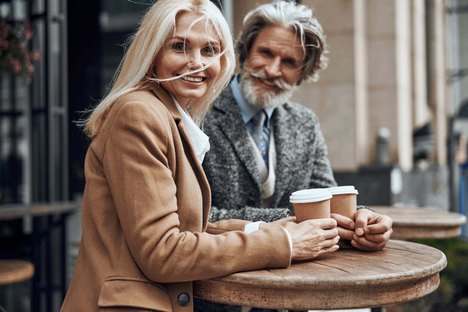 A couple in their sixties sitting with coffee at an outdoor cafe table